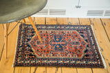 The vintage Hamadan rug's unique geometric central medallion in navy, rust, and ivory tones.