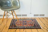 Vintage Hamadan rug featuring unique navy central medallion, rust red field, and fringed ends.
