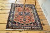 Vintage Hamadan rug's fringed end with rust red field and navy geometric border.