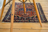 White fringe and geometric border with navy, rust, and ivory tones on vintage Hamadan rug.