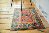Corner of vintage Malayer rug featuring peachy orange field and ornate mallard green border.