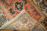 Vintage Malayer rug corner folded, showcasing dense pile, fringe, and peach, blue, ivory floral patterns.