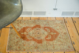 Antique Haji Jalili rug mat with madder red and gold hues in a styled room setting.