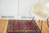 Vintage Persian Borchalou rug with cherry red field, blue medallion, and Herati floral motifs.