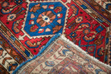 Borchalou rug corner revealing hand-knotted weave, cherry red field, and gem blue medallion.