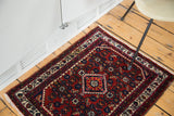 Engelas rug corner with cherry red field, gem-tone floral patterns, and time-softened ivory border.
