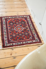 Hand knotted Engelas rug, cherry red field with gem-tone floral patterns, ivory border, and fringe.