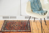 Engelas rug mat's rust red field with gem-toned floral motifs and part of the diamond medallion.