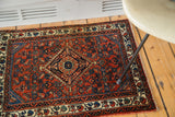 Rust red field, blue floral patterns, and patinated ivory border on vintage Engelas rug.