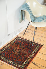 Corner view of Engelas rug mat, featuring gem-tone rust red floral motifs and fringe.