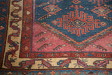 Antique Malayer rug corner showing indigo field tribal motifs, serrated pink, and wavy beige borders.