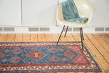 Antique Malayer rug featuring geometric tribal design, human figures, birds, and serrated leaves on an indigo field.
