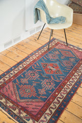 Indigo field detail of antique Malayer rug with geometric motifs, stylized human figures.