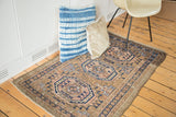 Tribal Belouch rug detail: geometric gul, arrow border motifs in muted pink, navy, tan.