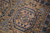 Hand-knotted vintage Belouch rug detail: tribal gul with arrow elements in rose, navy, brown.