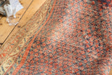 Vintage Persian rug detail with navy blue and rust red repeating boteh, revealing cotton foundation.