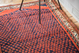 Vintage Persian rug detail: rust red boteh field on navy blue with ornate border.