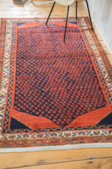 Vintage Persian rug border with intricate ivory, blue, and rust red motifs, revealing clean cotton foundation.