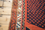 Rust red boteh on navy field, framed by saffron, ivory, blue geometric Persian rug border.