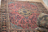 Distressed vintage Sarouk rug with dusty raspberry tendrils, teal spandrel, palmette border.