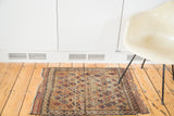 Antique Belouch rug, repeating pinwheel design on natural brown field, with visible age.