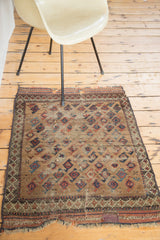 Lower corner of the antique Belouch rug with a red repair patch, worn fringe, and geometric pattern.