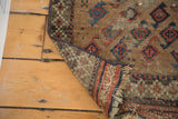Antique Belouch rug mat corner showcasing its woven back, madder red and navy pinwheel motifs.