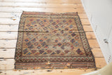 Antique Belouch rug's frayed bottom edge, revealing pinwheel motifs and time-softened wool.