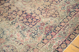 Ornate milfleur field and traditional border detail of an antique Kerman rug in rose, sand, and navy.