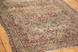 Antique Persian Kerman rug's ornate milfleur field with muted red, blue, and beige motifs.