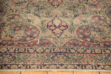 Detail of the antique Kerman rug's ornate border, milfleur field, and short fringe.