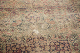 Intricate milfleur pattern on antique Kerman rug with faded red, dark blue, and sand tones.