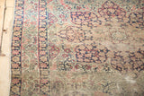 Ornate milfleur field with intricate dark blue and faded red floral border on the antique Kerman rug.