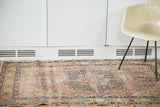 Antique Kerman rug's ornate trefoil medallion, germinating plant motifs, and visible wear.
