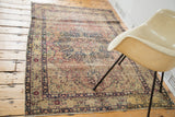 Antique Kerman rug's aged beige, rose, and indigo floral motifs with curvilinear border.
