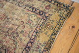 Antique Kerman rug corner with trefoil plant motifs in muted red, dark indigo, showing wear.
