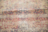 Antique Kerman rug's time-softened tones, storied wear, and trefoil germinating plant motifs.