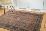 Antique Tabriz rug's navy border and distressed herati field with softened brick rust.