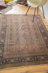 Bottom corner of the Antique Tabriz rug, featuring distressed pile and deep navy floral border.