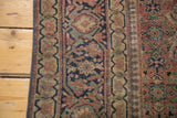 Mended navy binding and distressed curvilinear border of an antique Tabriz rug.