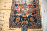 Lower section of distressed antique Persian Malayer rug: worn navy field, madder red design, frayed edge.