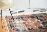 Distressed pile and frayed edges of an antique Persian Malayer rug in madder red and navy.