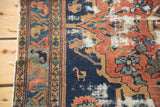 Frayed edge, geometric border, and stylized animal on the indigo field of an antique Malayer rug with distressed pile.