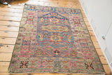 Vintage Lilihan rug corner with intricate blush, blue, saffron motifs and clean fringe.