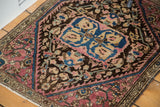 Angled view of antique Sarouk rug's floral patterns in plum, blue, and brown, size 1'11