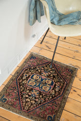 Angled view of the antique Farahan Sarouk rug mat with plum and blue details, measuring 1'11