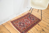 Vintage Karaja rug upper left corner: brick red field, navy, ivory geometric motifs.