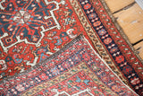 Vintage Karaja rug corner showing original overcasting and intricate brick red, navy borders.