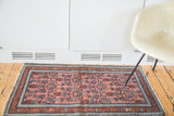 Malayer rug's dusty rose floral field, blue running T and flower-arrow borders.