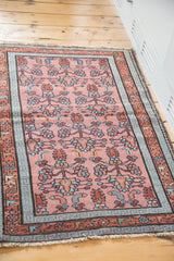 Detail of Persian Malayer rug showing dusty rose field, blue meander, and red floral borders.
